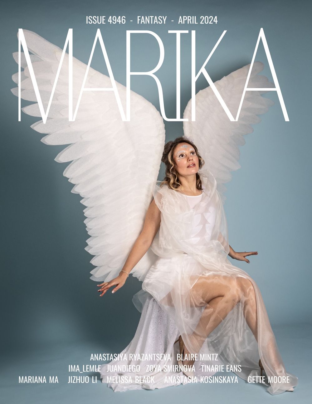 Magazine cover with ethereal figure in flowing white dress and large angel wings against blue-gray backdrop.