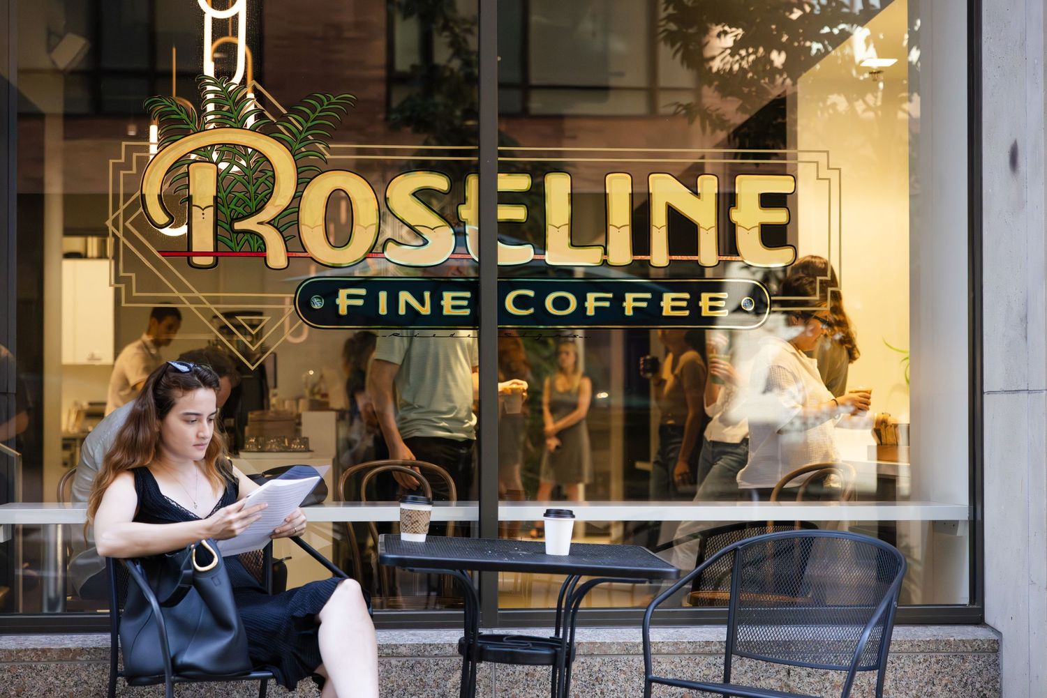 Exterior of Roseline Fine Coffee shop with outdoor seating and patrons enjoying coffee on a sunny day.