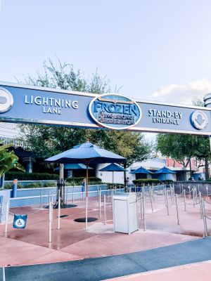 Empty Disney World queue area with covered waiting lines and railings under blue Lightning Lane entrance sign.