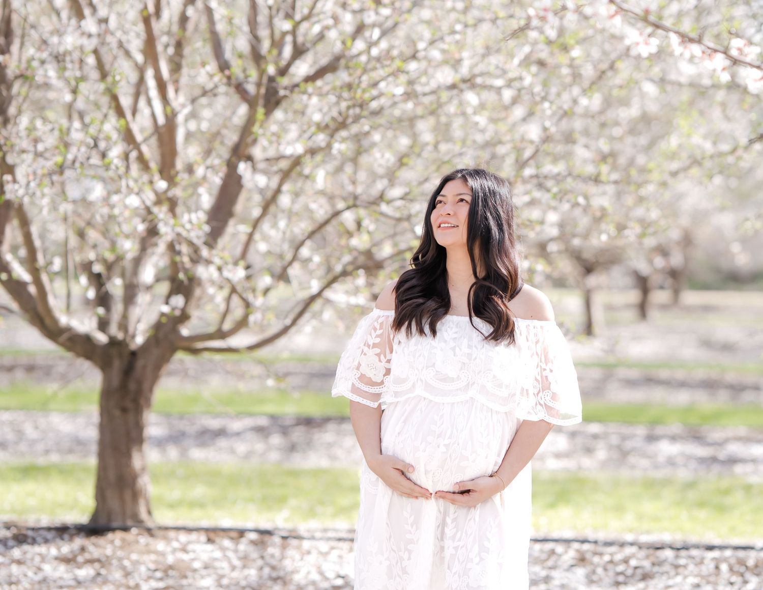 Expecting couple walking hand-in-hand under the cherry blossoms, creating timeless memories during a beautiful maternity photoshoot in Sacra