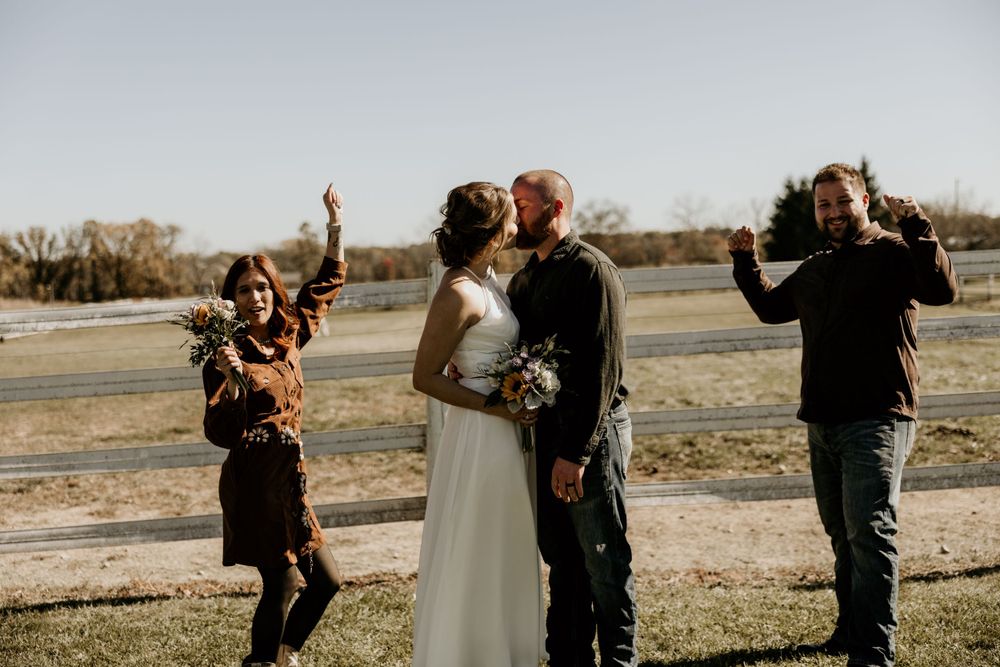 A couple sharing a romantic moment outdoors while photographers capture their special day in autumn.