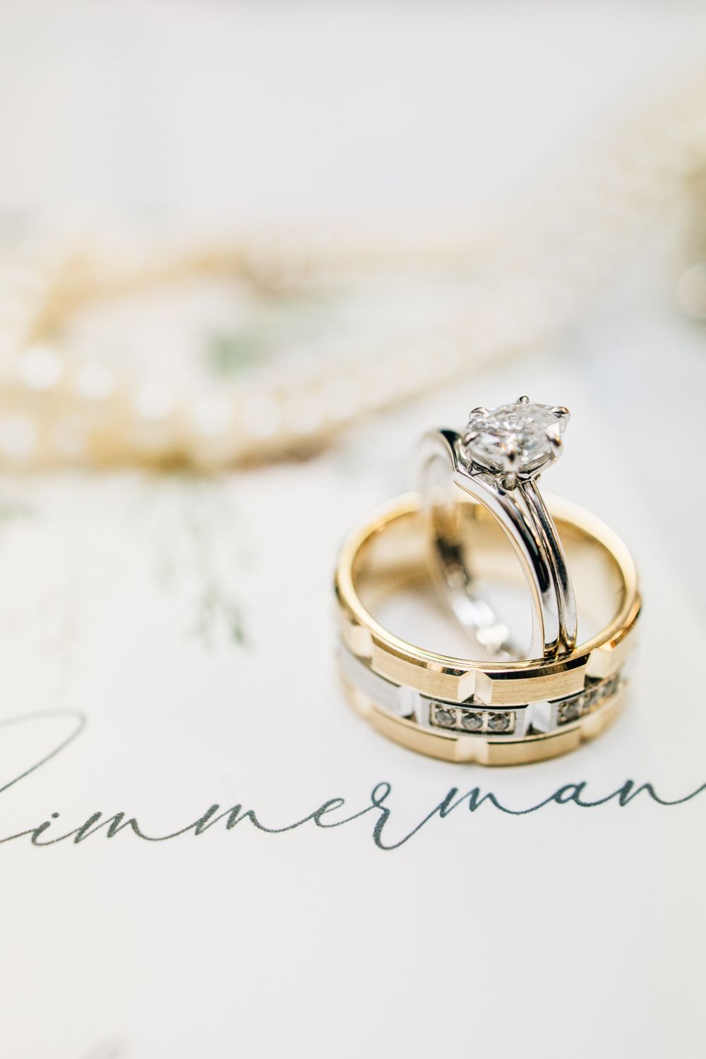 Diamond engagement ring and gold wedding band set displayed on elegant calligraphy.