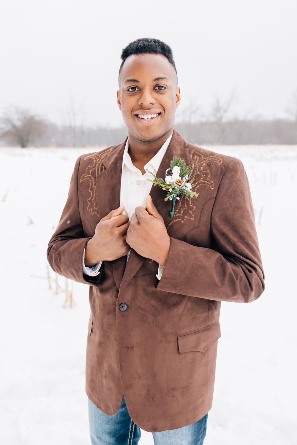 Wedding portrait in the snow featuring a brown suede jacket and boutonniere.