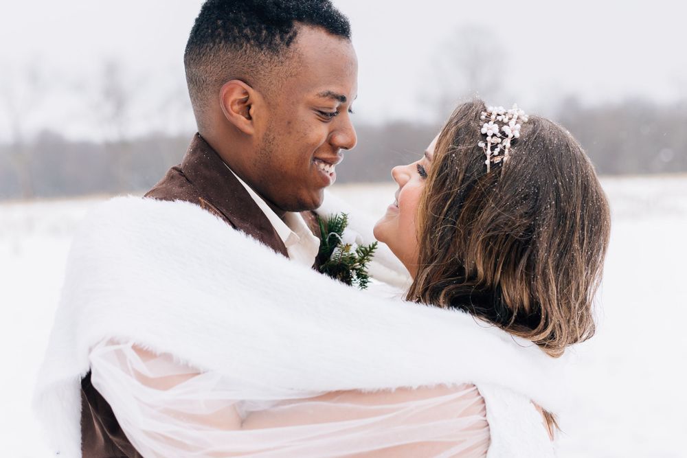 A romantic winter wedding photo featuring an intimate moment between newlyweds against a snowy backdrop.