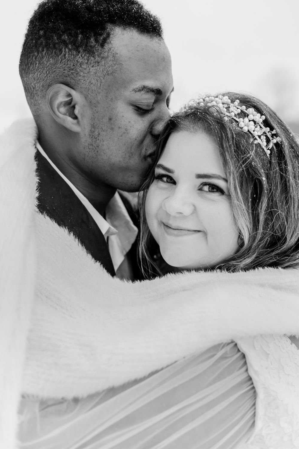 A black and white wedding portrait captures a tender moment between a bride and groom.