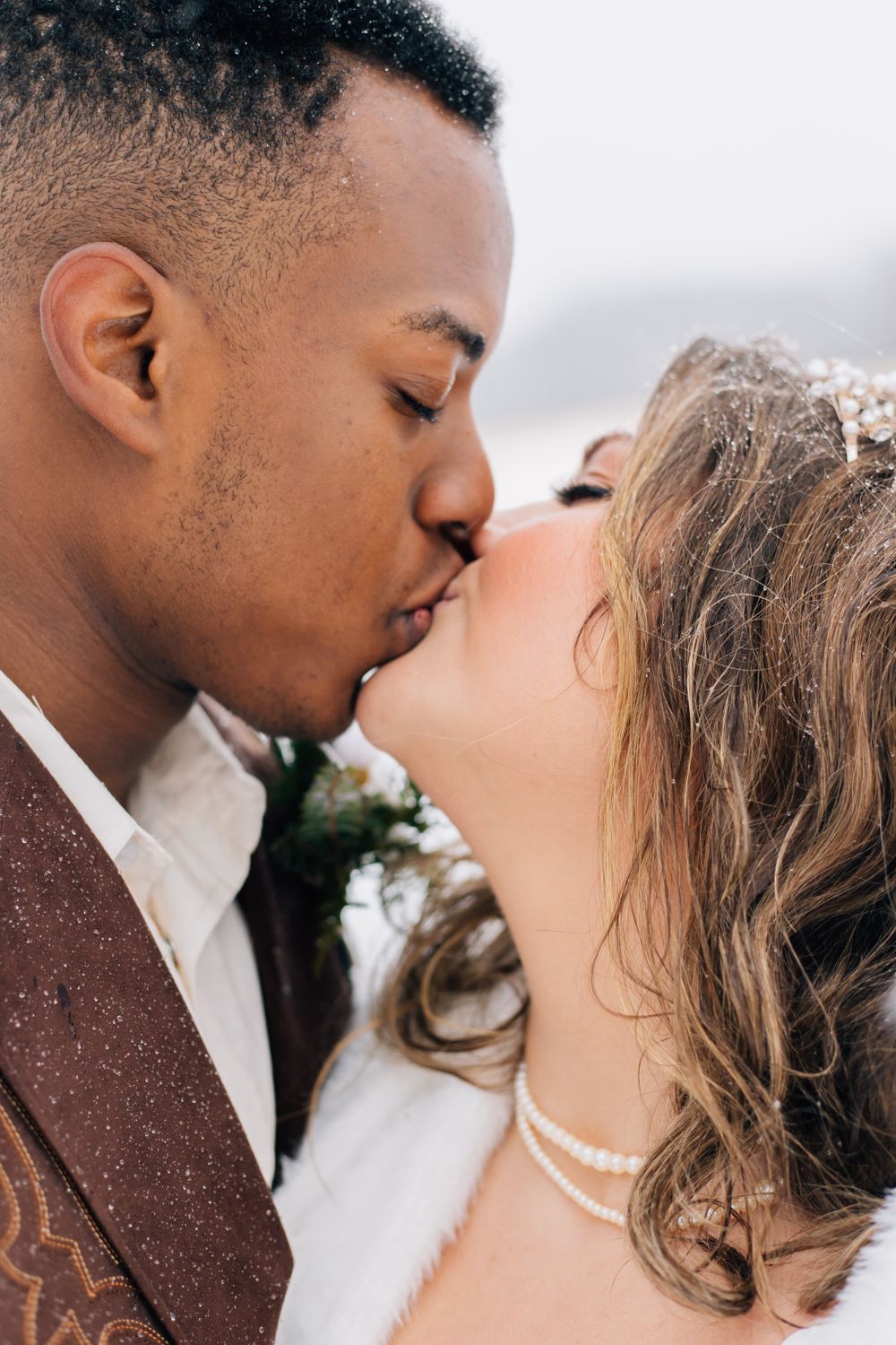 An intimate close-up wedding photo capturing a romantic kiss in a winter setting.