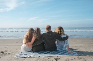 Family of four looking out at ocean in Coronado CA sitting on blanket looking out at ocean