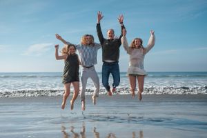 Family of four smiling and jumping in the water at beach in Coronado CA