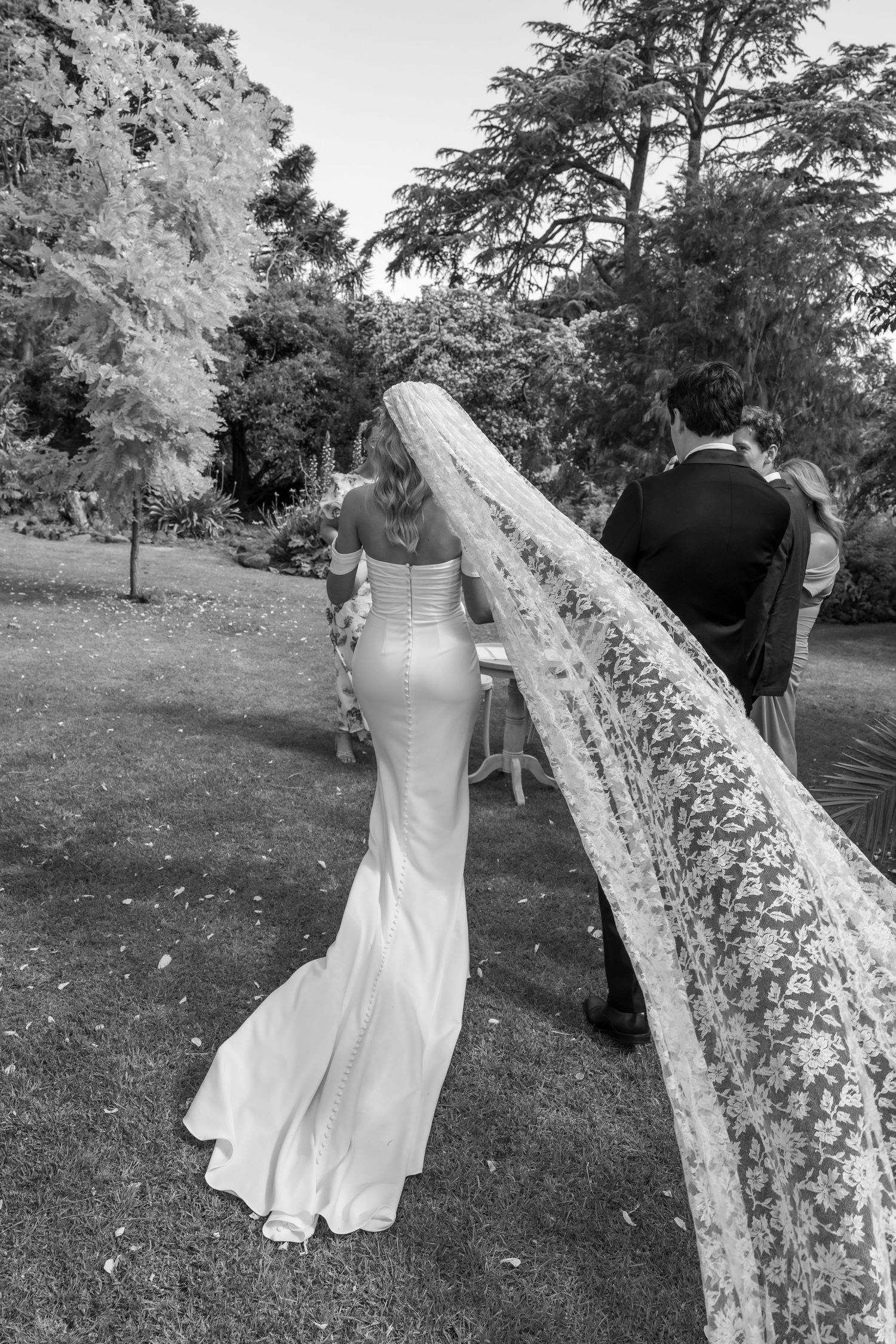Intimate wedding portrait with couple in formal attire against stone wall background.