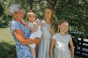 Multi-generational group in summer attire poses together outdoors on a sunny day.
