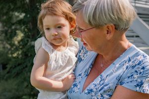 A small child and older person sharing a tender moment outdoors in summer attire.