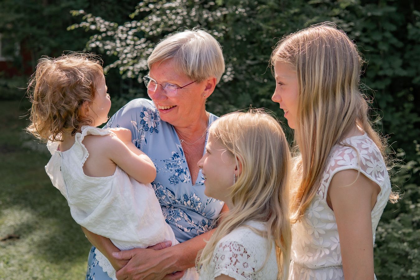 Family group enjoying a summer day together outdoors in a garden with white lace dresses.