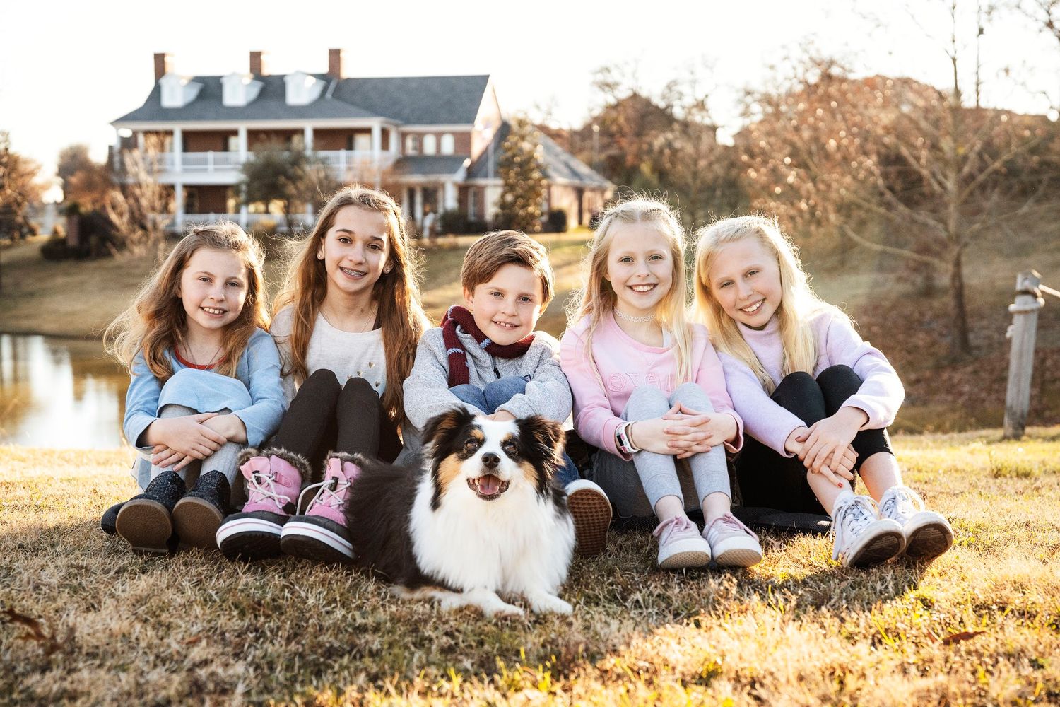 Extended family sitting together outdoors with their pets on autumn day.