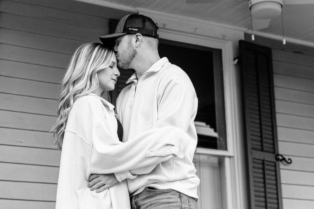 Black and white photo of hugging and kissing couple taken in downtown Dandridge, TN by couples photographer in East Tennessee.