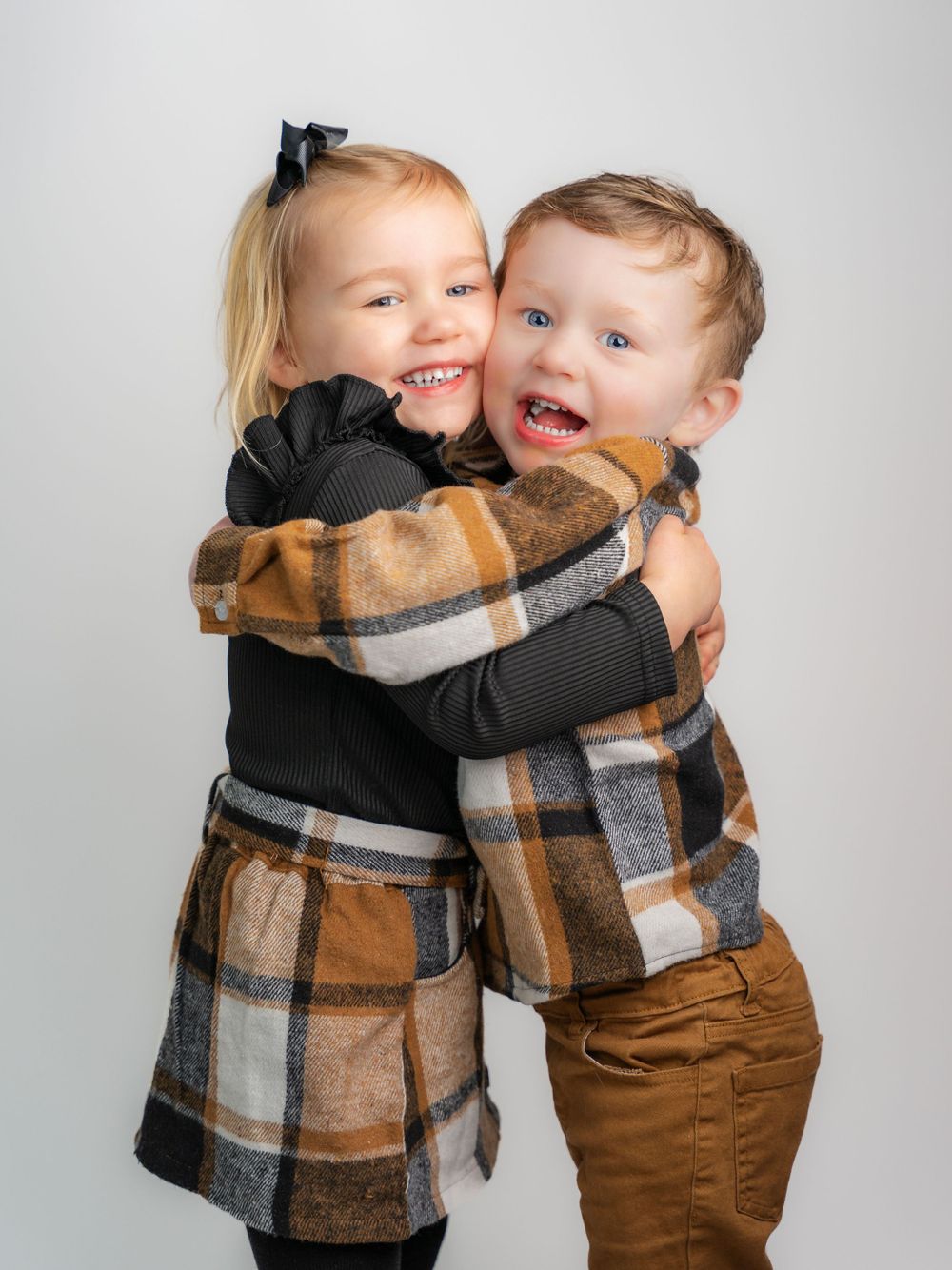 Children's portrait of 2 toddlers hugging in matching outfits taken in East Tennessee family portrait photographer's studio