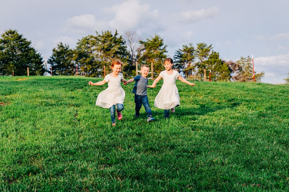 Picture of 3 young children playing ring around running down a hill taken by Dandridge family and children photographer