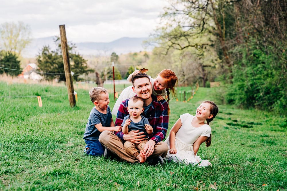 Photo of a father and his children sitting on the grass on a farm in Dandridge by East TN iifestyle and family portrait photographer.