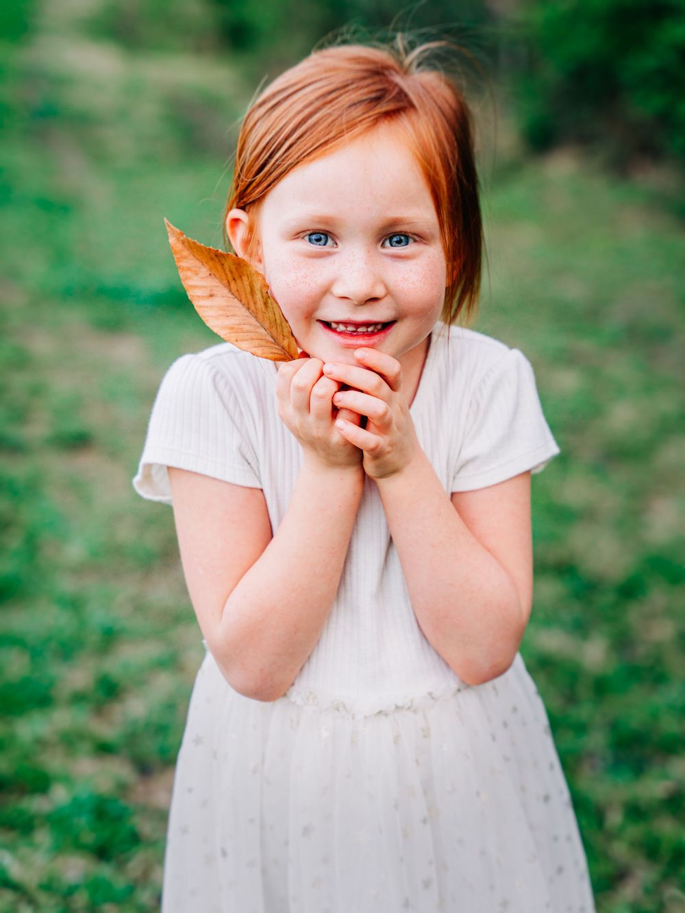 Portrait of a little girl with red hair holding a red leaf taken on a farm by Jefferson County TN children's photographer