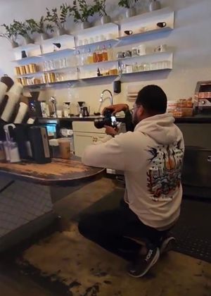 Photographer taking product shots in a modern coffee shop interior.