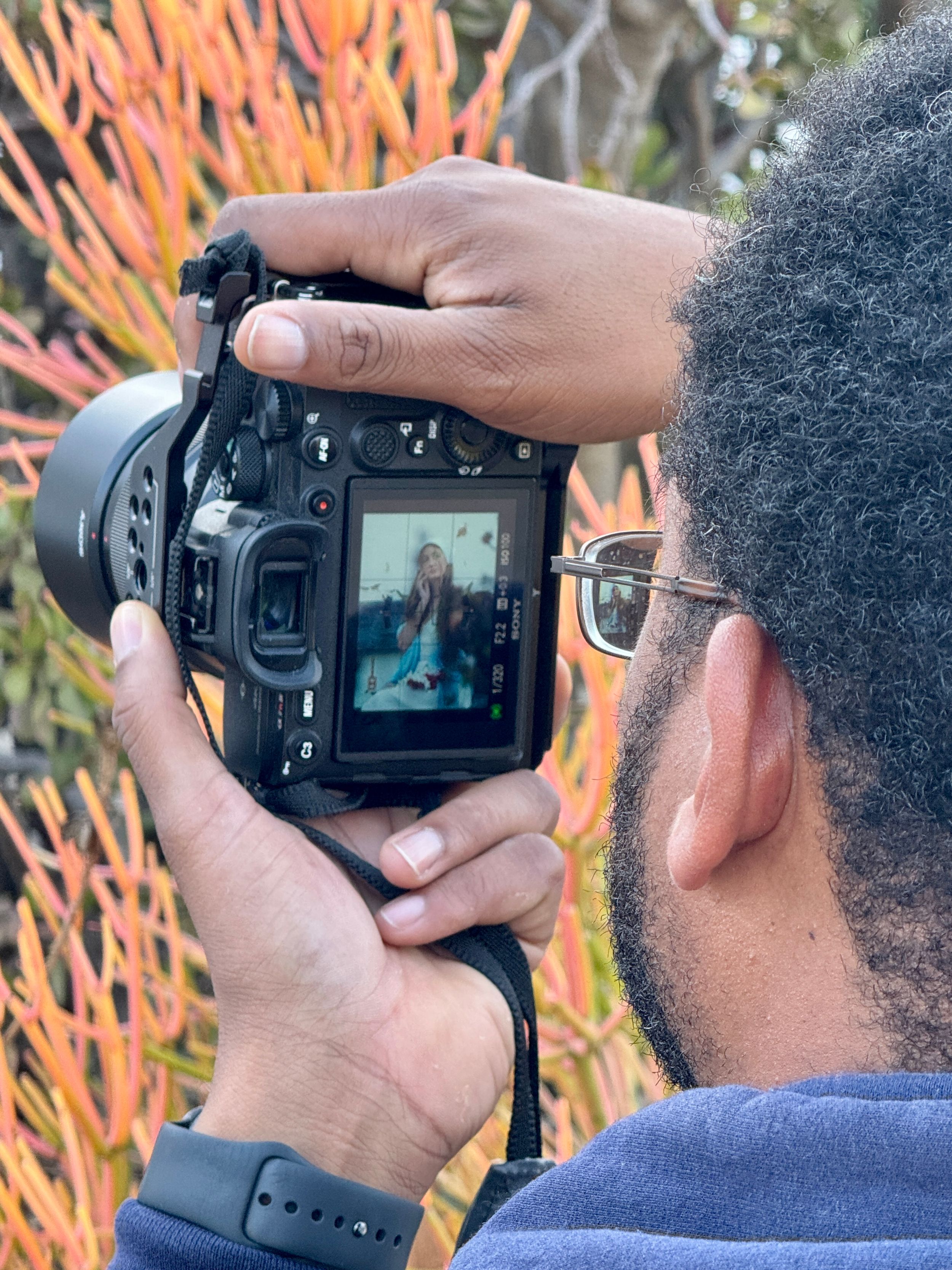 Close-up of photographer reviewing images on camera display with colorful background.