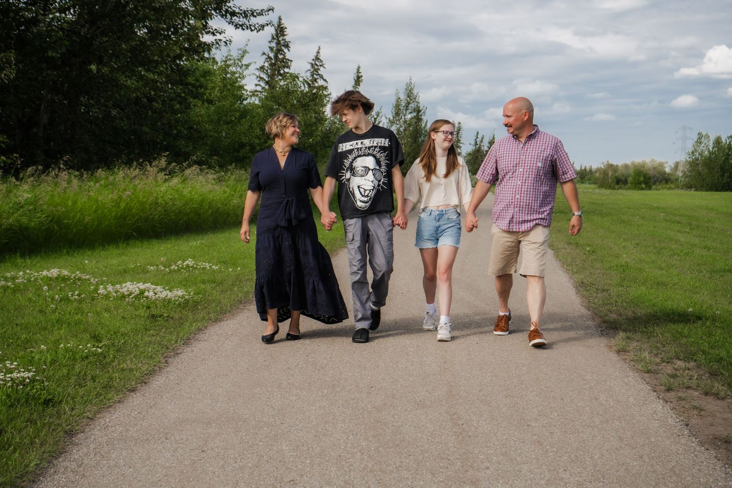 Family of four walking together on a paved trail surrounded by nature.