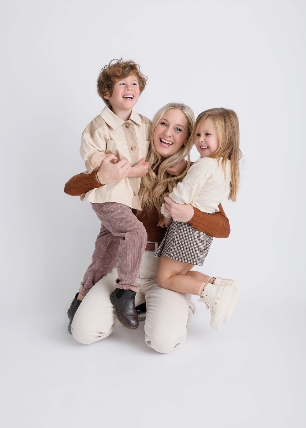 Joyful family photoshoot with matching outfits and genuine laughter against white background.