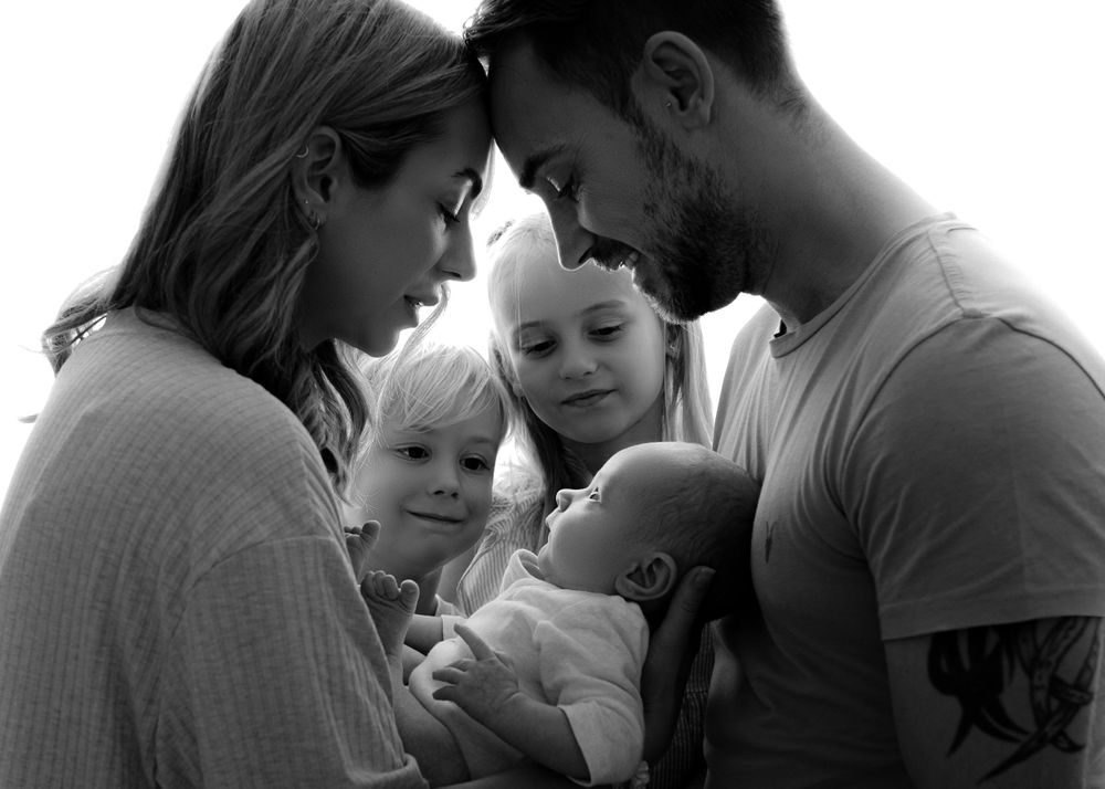 A tender black and white family moment with parents lovingly gathered around their young children.