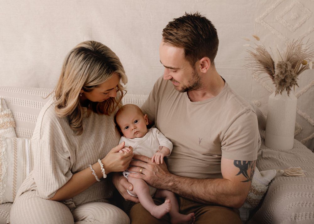 Tender family moment captured in soft neutral tones against light background.