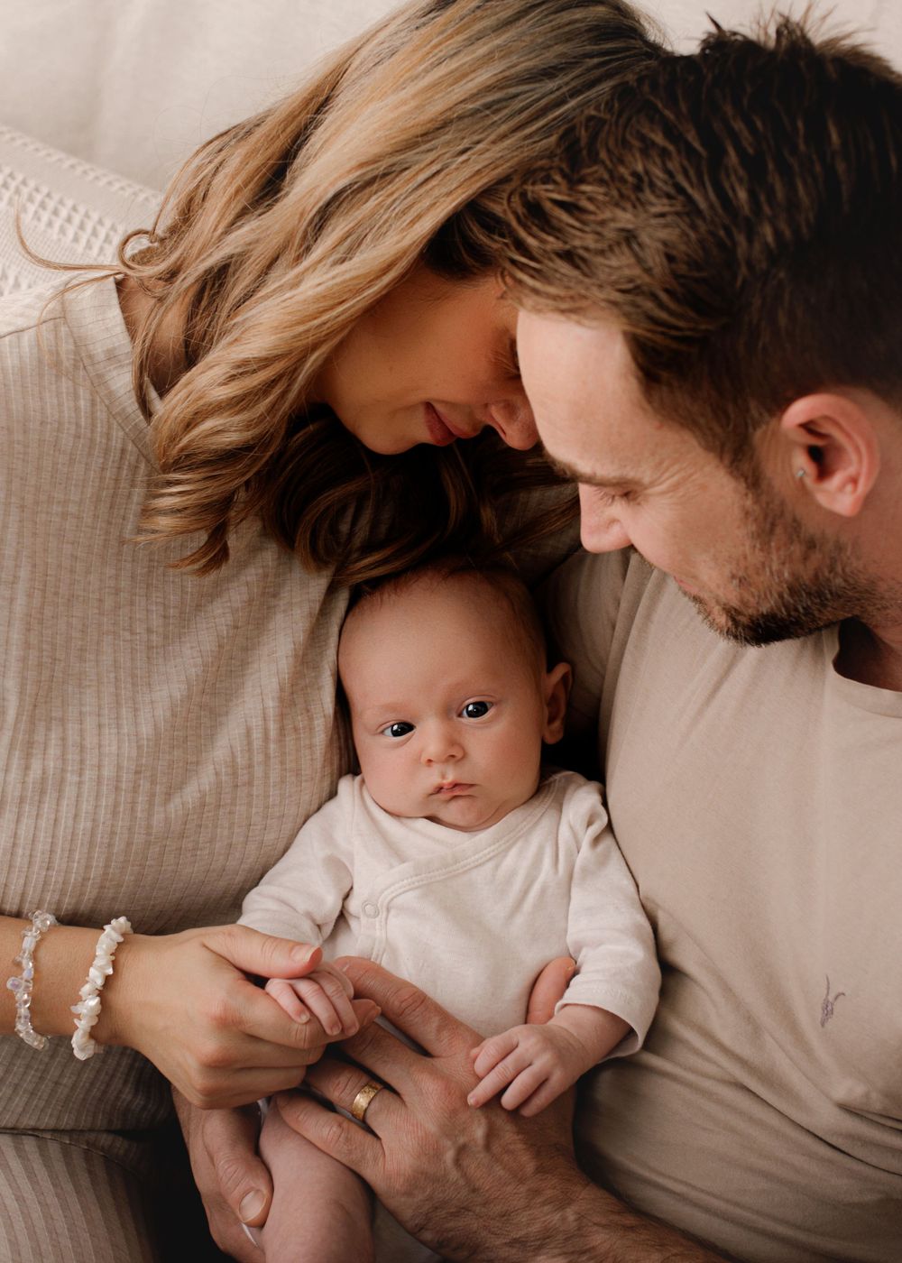 Intimate family portrait in neutral tones showing tender moment together.