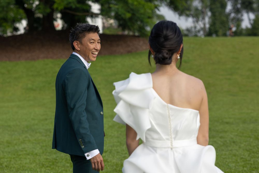 Wedding couple sharing a candid moment on lush green lawn.