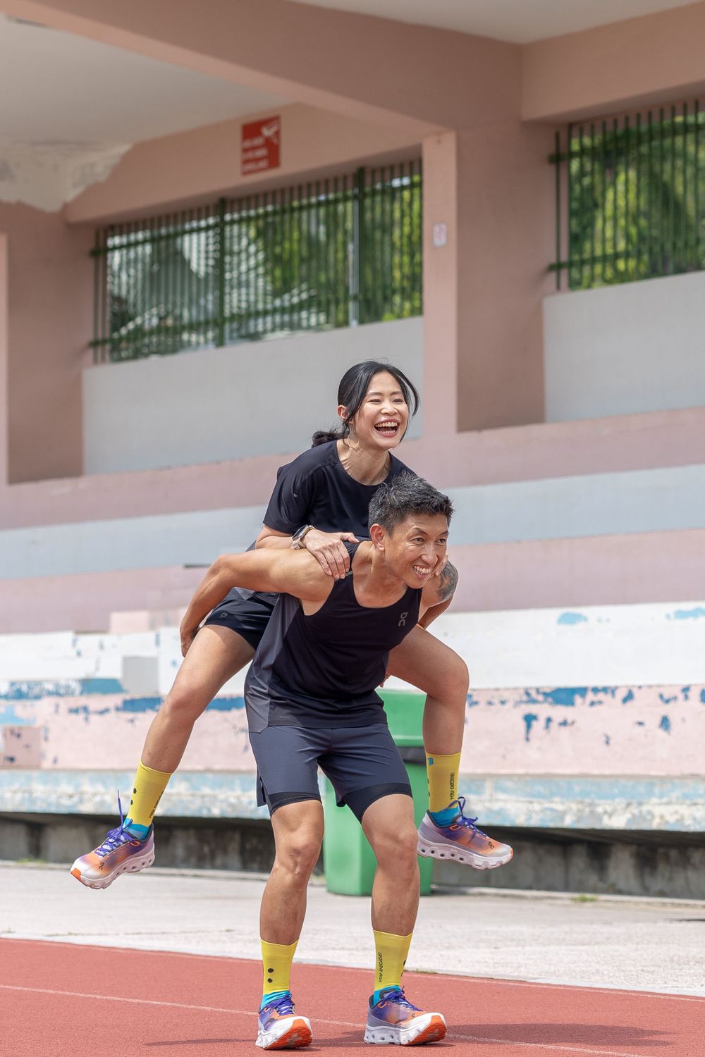 Two people having fun with a playful piggyback ride at an outdoor sports facility.