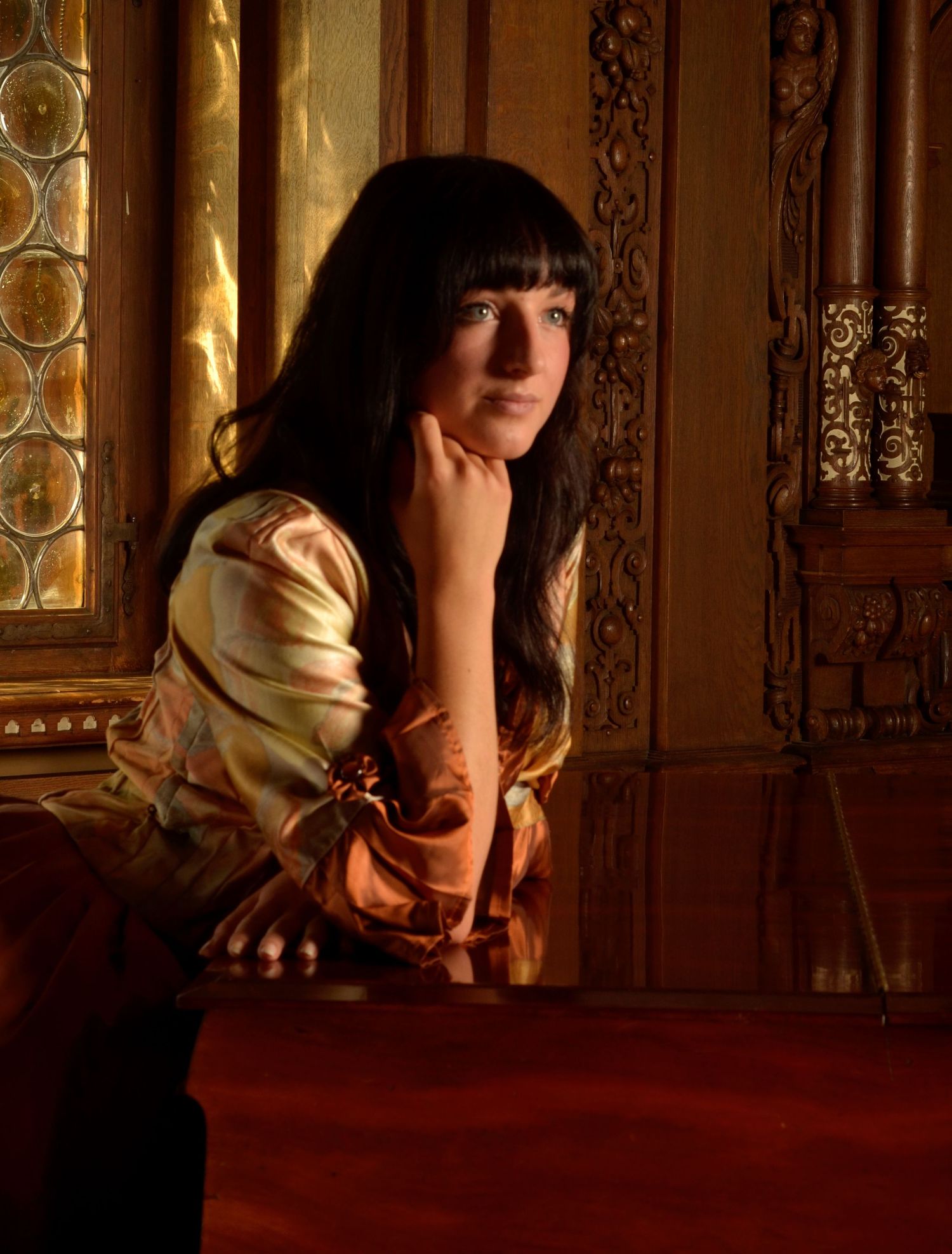 Artistic portrait in a medieval-style setting with ornate decor and warm lighting.