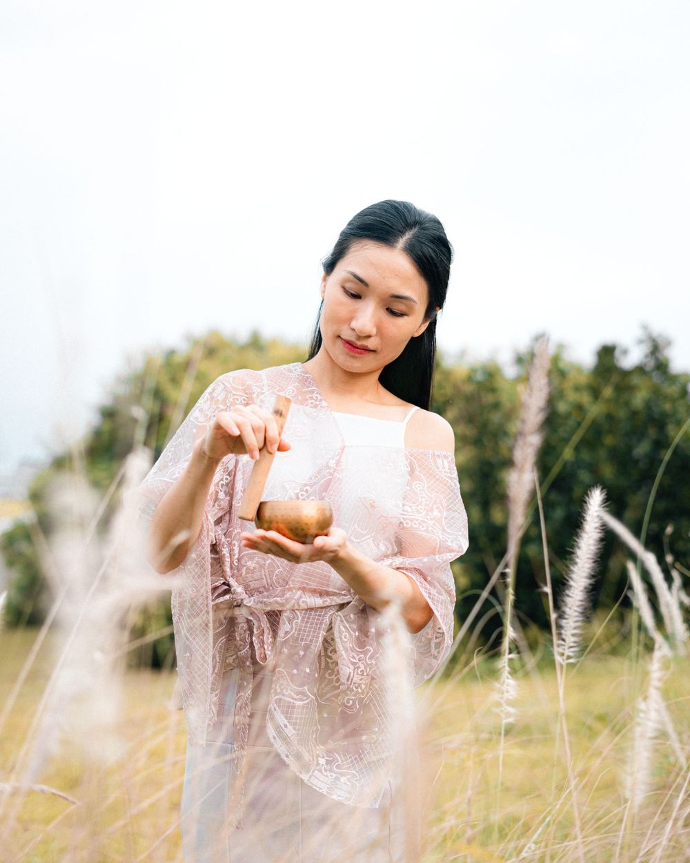 Soft pink lace dress contrasts beautifully against wild grasses in natural lighting.