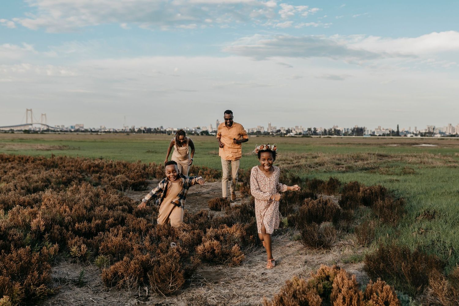 Family walking together through natural marsh landscape at sunset.