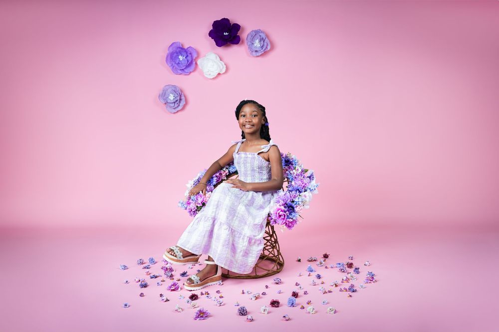 Purple and white floral decorations arranged against a pink studio backdrop.