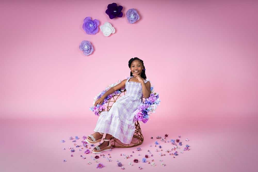 Purple and white floral decorations arranged artistically on pink backdrop.