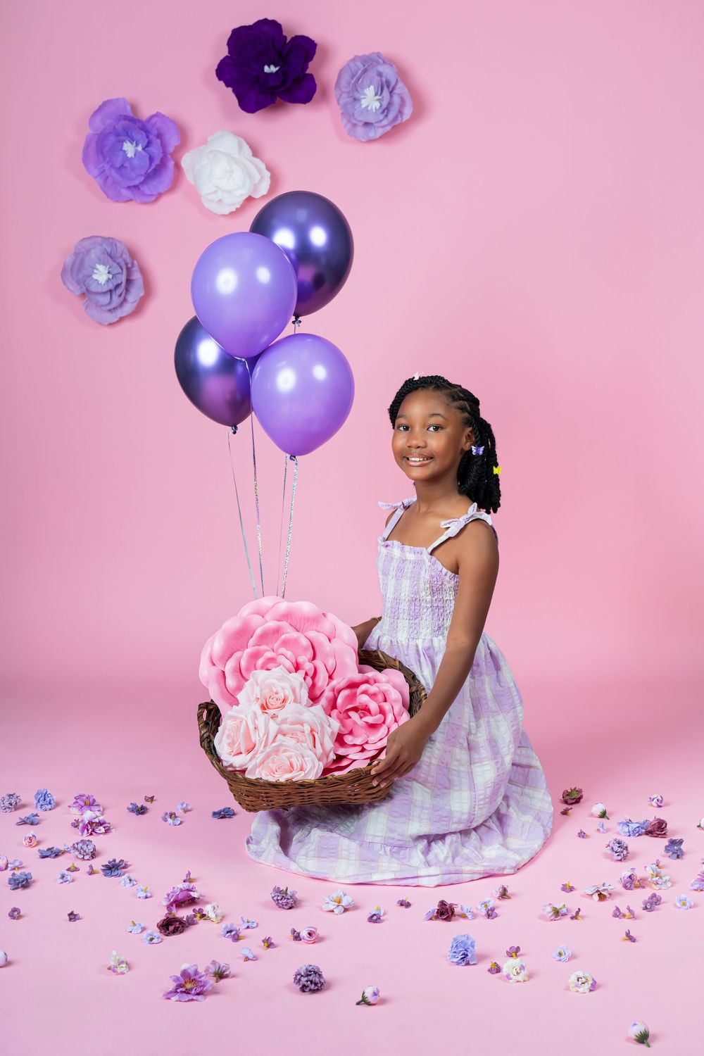 A pink birthday setup with purple balloons and paper flowers creates a whimsical celebration scene.