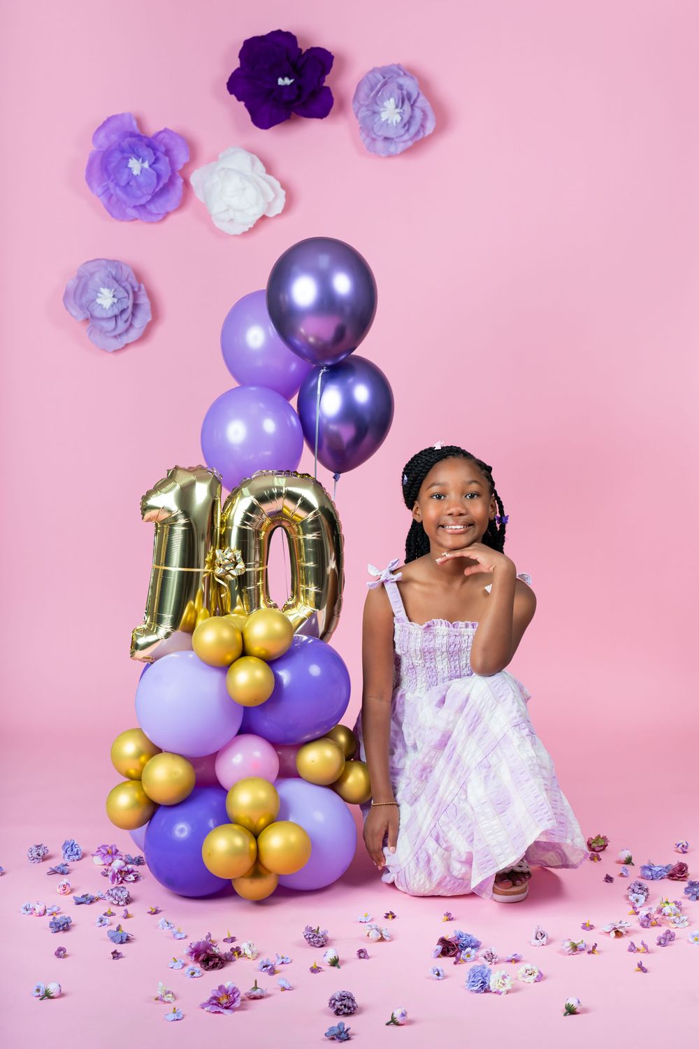 Festive birthday display with gold and purple balloons, paper flowers, and pink decorations.