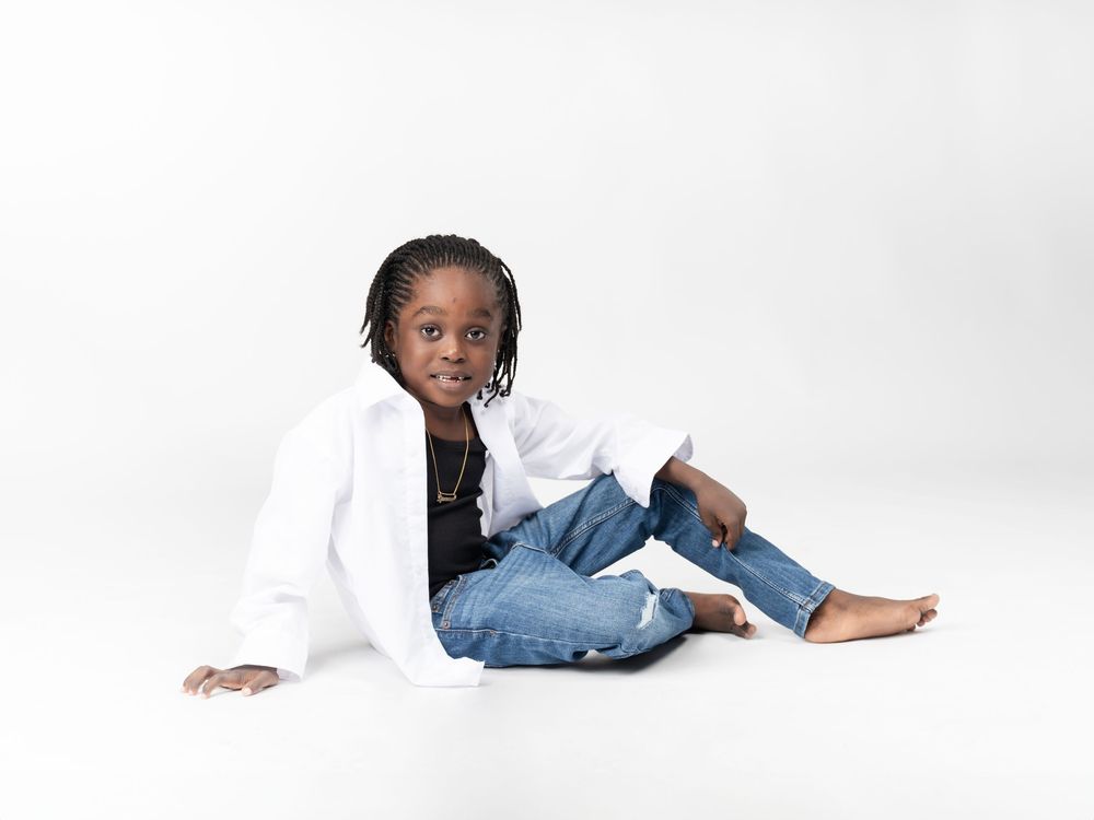 Casual studio photography session with white backdrop and denim styling.