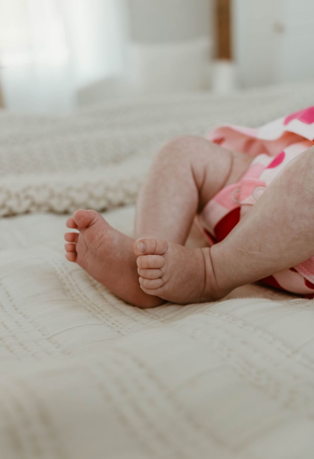 Close-up of tiny baby feet resting on white textured bedding.