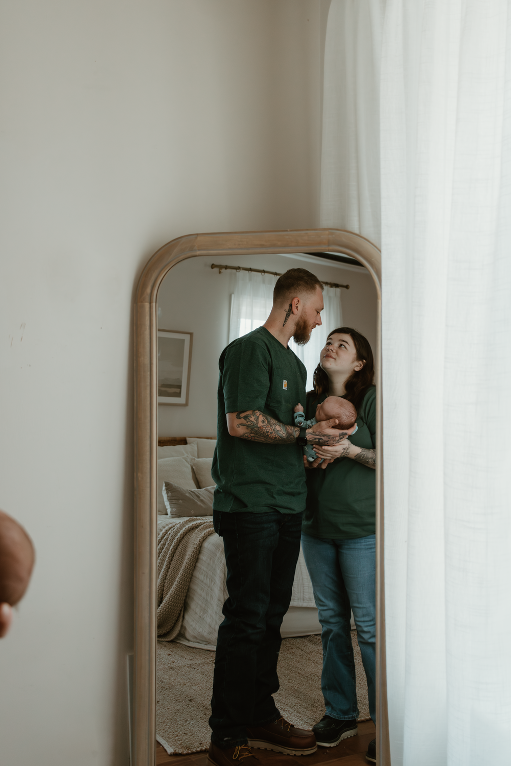 Mirror reflection captures tender family moment as parents hold their newborn.