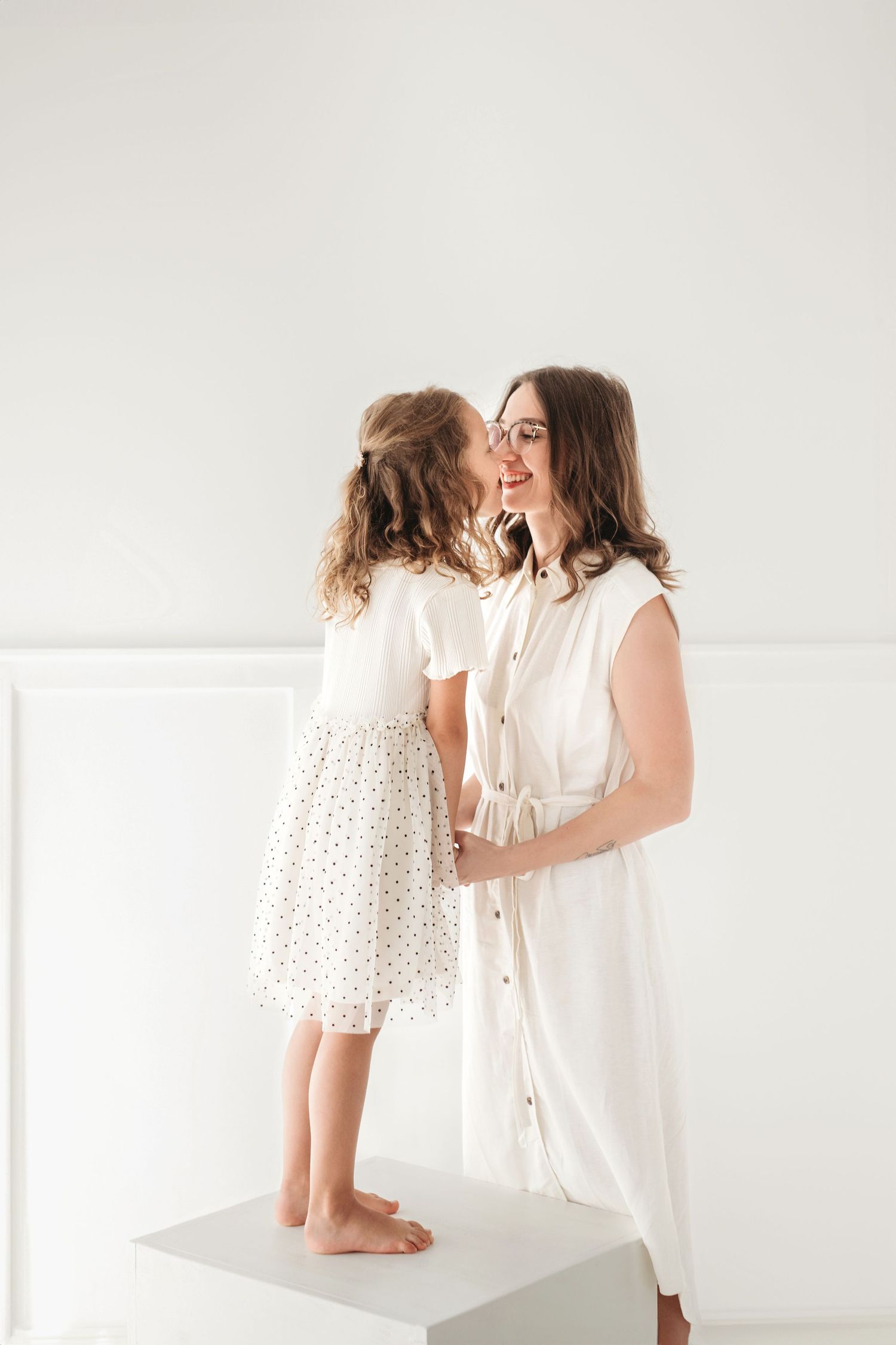 A sweet moment captured in white as they share a loving interaction against a minimalist background.