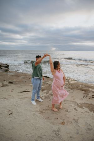Beach maternity session, pink dress, La Jolla beach, dancing on the beach