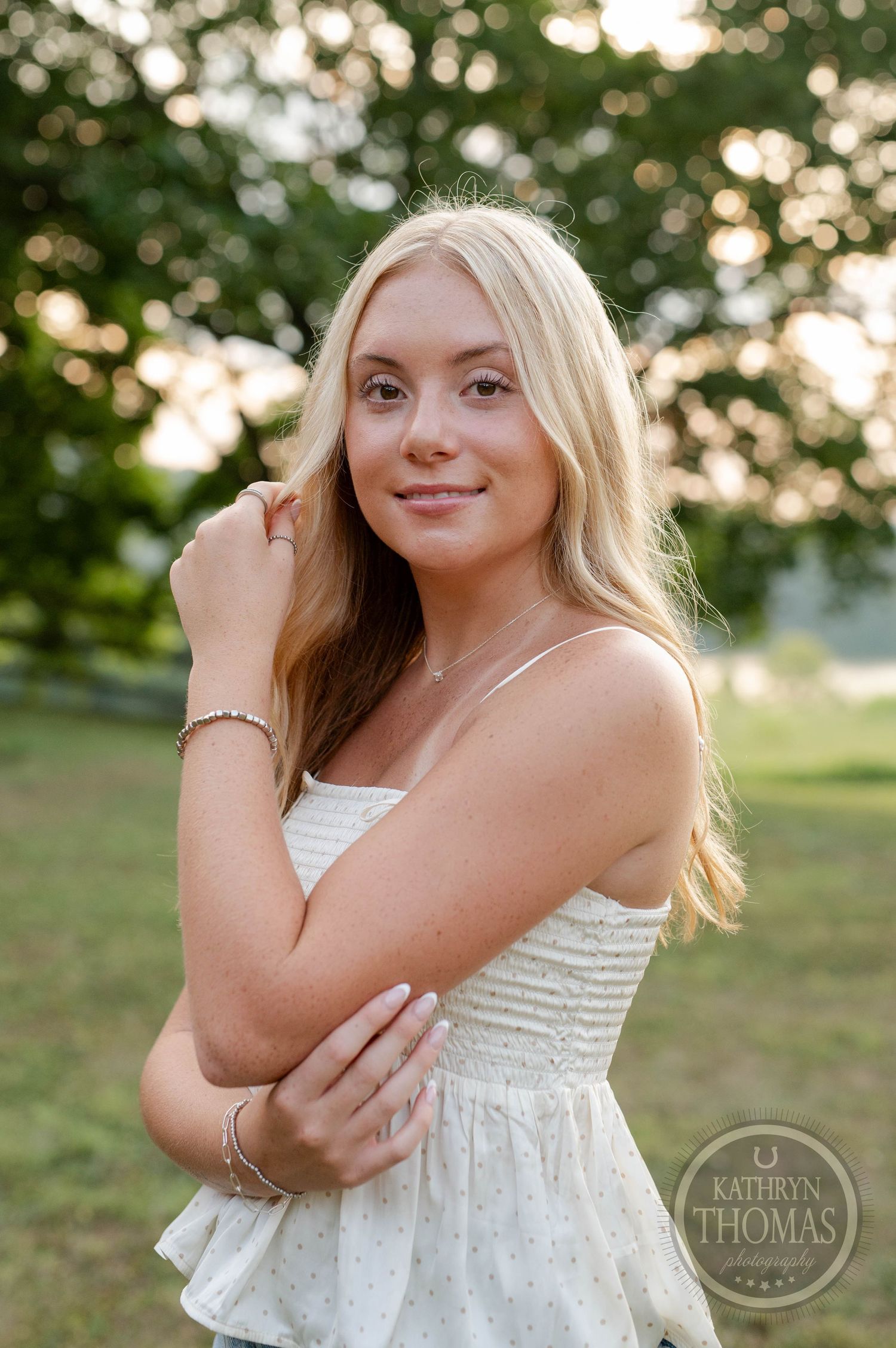 Natural light portrait in white summer dress against blurred green background during golden hour.