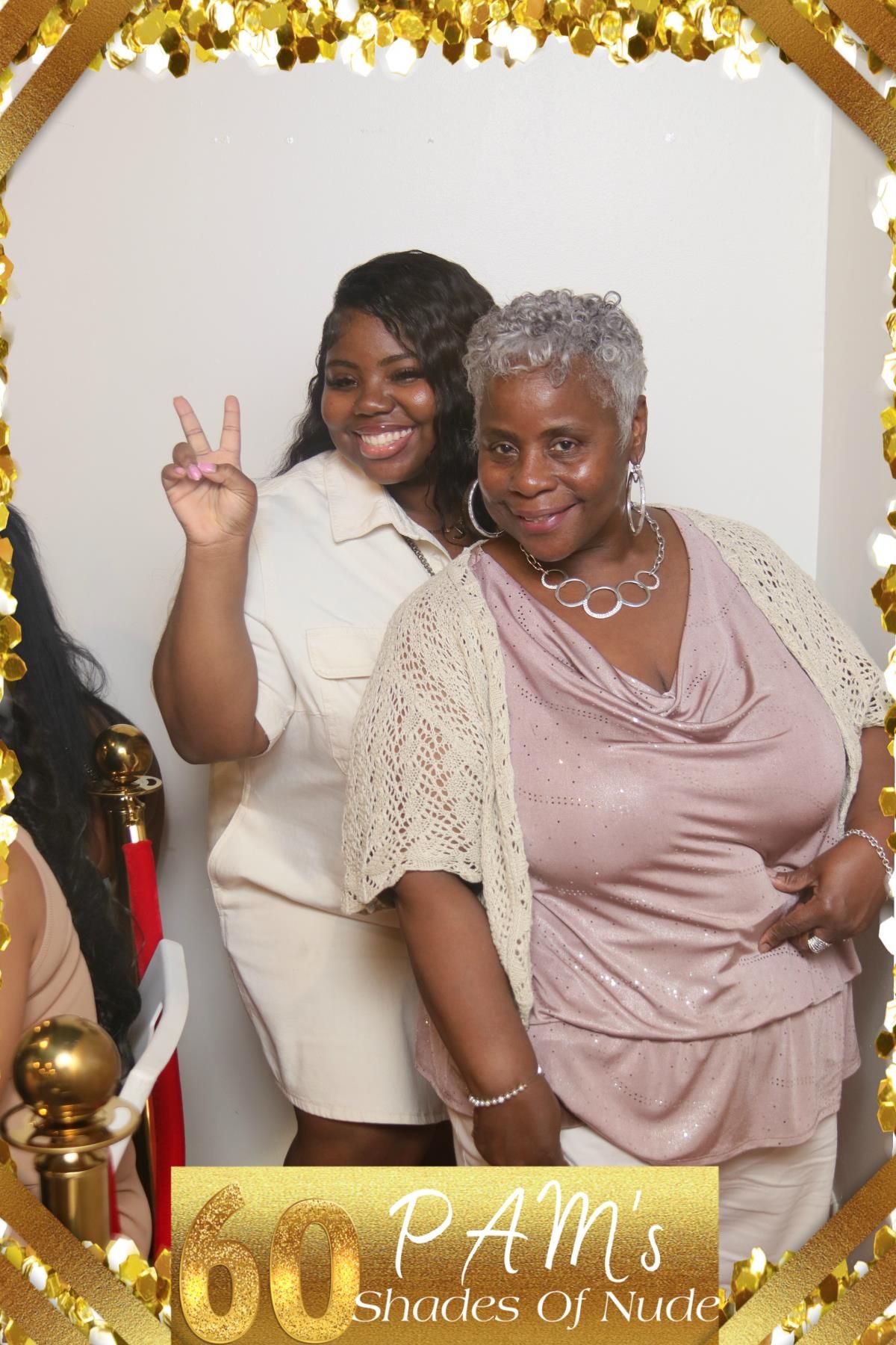 Two individuals pose together at a festive event with gold decorations against a white backdrop with "60 PAM's Shades of Nude" text.