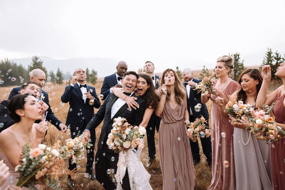 Wedding party celebrates outdoors with joyful expressions and floral bouquets in mauve dresses.