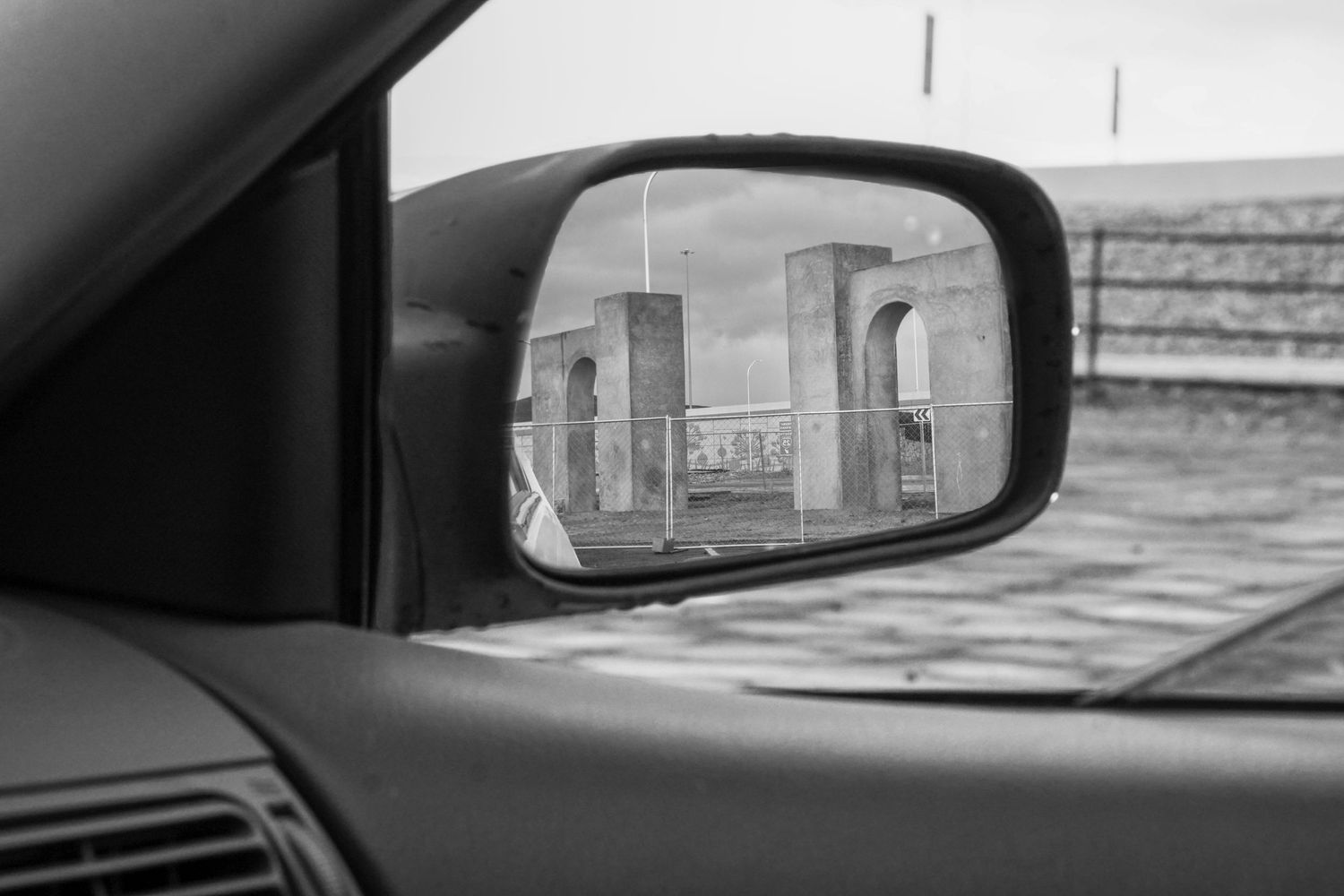 Two monuments, a construction project, reflecting in a car mirror