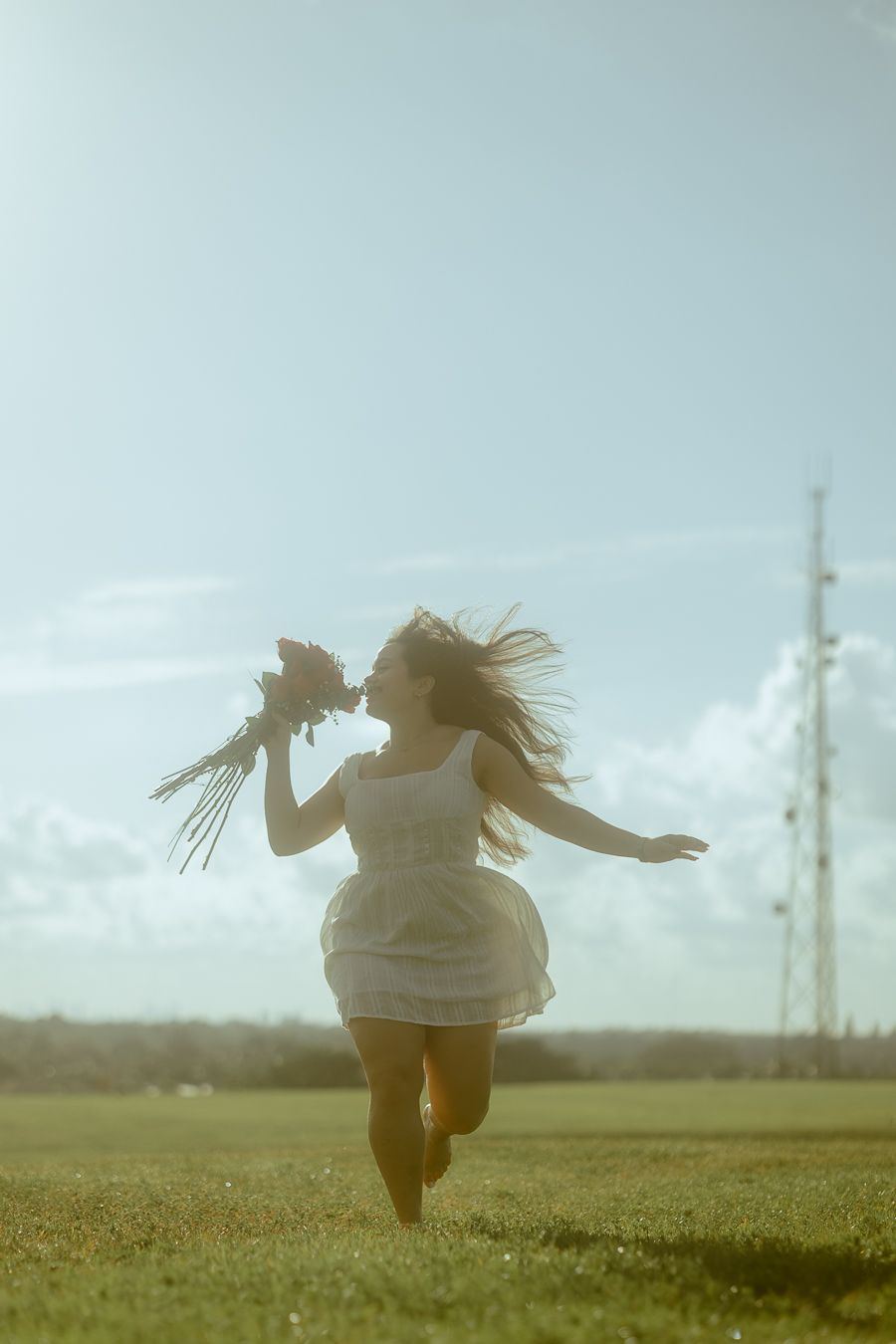 Golden-hour portrait of young woman running barefoot in a field with flowers, South Florida cinematic photoshoot testimonial.