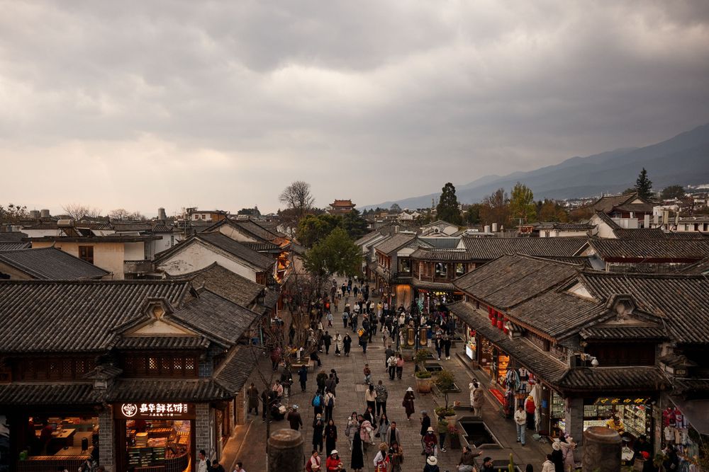 Ancient street lined with traditional Chinese architecture in Lijiang Old Town under moody overcast skies.