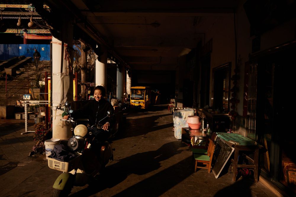 Motorcycles parked in a dimly lit covered area at night with various items scattered around.